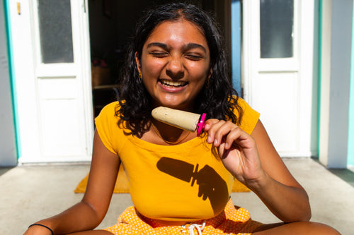 Meera's Cardamom & Rose Water Kulfi being eaten by a person wearing yellow in the sun!