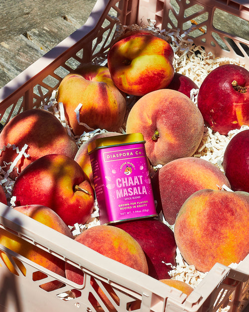 Fruit box filled with peaches and a tin of chaat masala