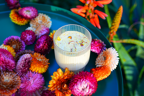 Shivani's Masala Doodh in a glass served on a blue tray with flowers for decoration.